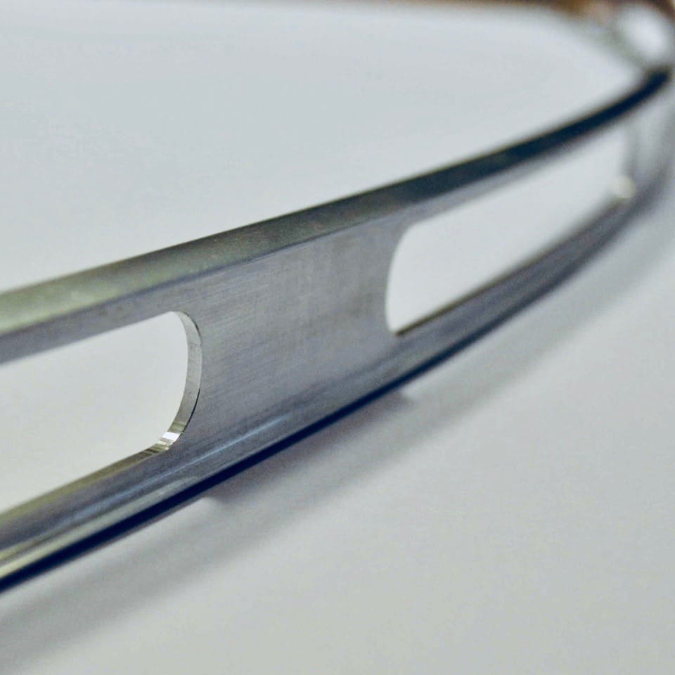 Close up of bent aluminium part with machined slots in mill finish
